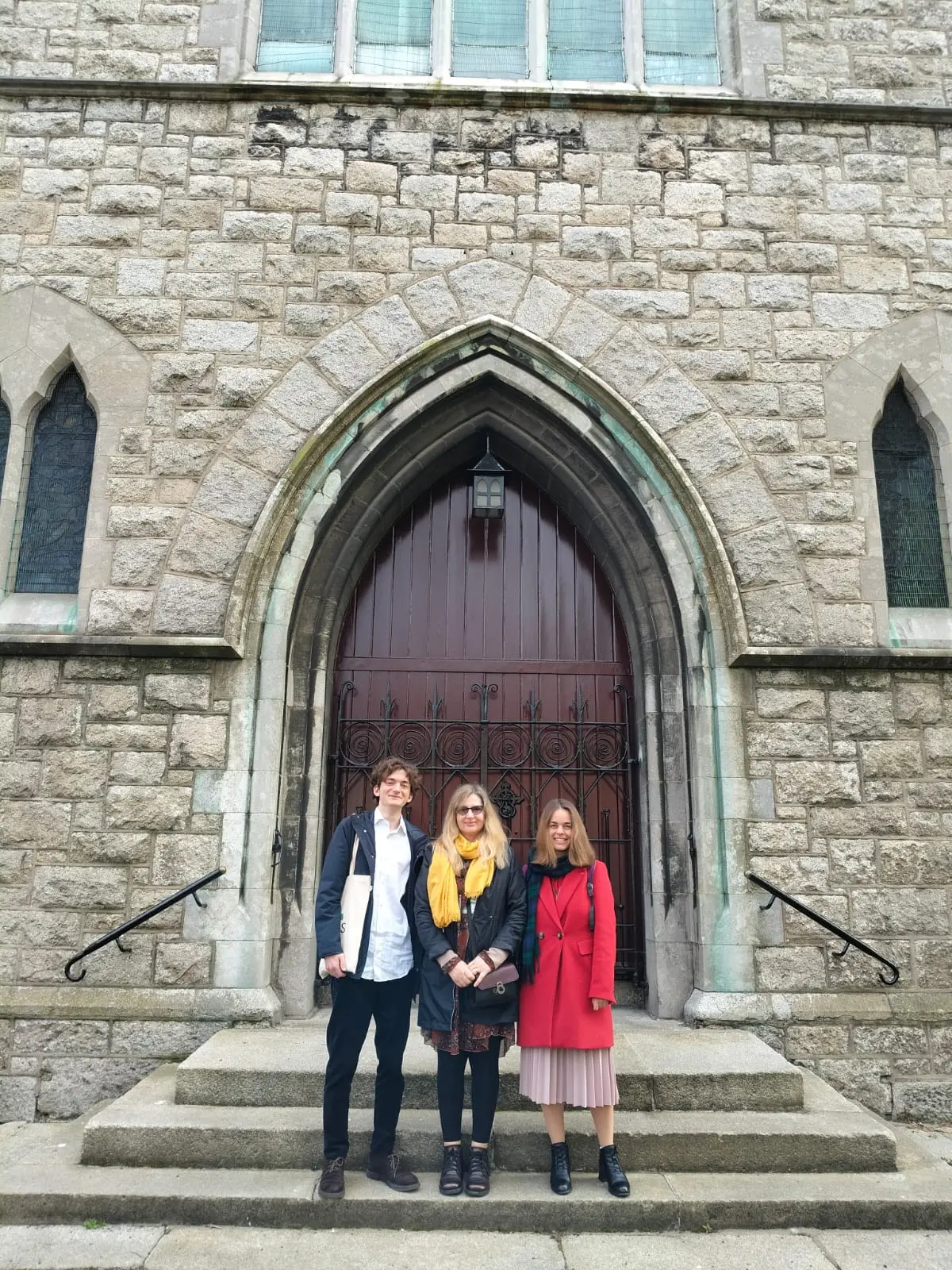 Trei participanți la colocviu în fața unei biserici de piatră din Dublin