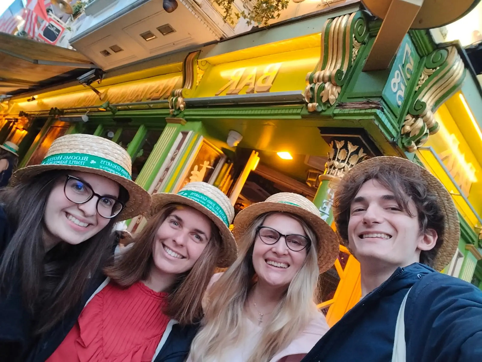 Selfie cu patru tineri cu pălării de paie, în fața unui pub din Dublin